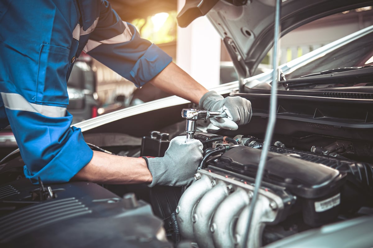 Mechanic using a wrench to repair a car in the driveway