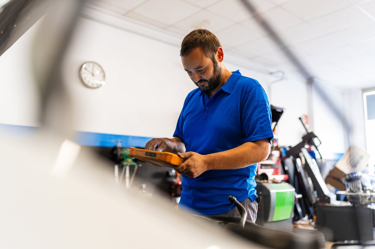 Mechanic checking vehicle systems with a diagnostic tablet